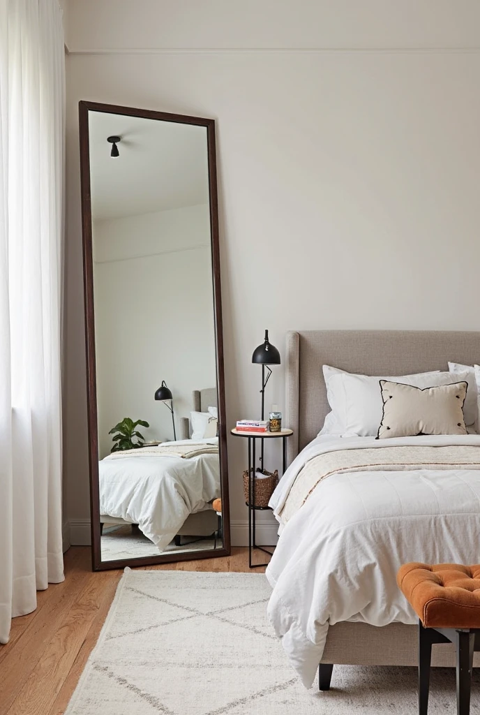 A chic and inviting bedroom featuring a large statement floor mirror opposite the bed, serving as the focal point of the room. The mirror is oversized, with a sleek, modern design—geometric frame and minimalist rectangular style. Its reflective surface not only amplifies the natural light but also creates the illusion of a larger, more expansive space. The room is styled with soft, neutral tones—light grays, whites, and warm wood accents—allowing the mirror to stand out while seamlessly integrating with the overall décor. The cozy bedding, simple nightstands, and tasteful lighting complement the room’s airy, balanced feel, making the space feel more open and visually interesting.